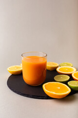 Glasse of healthy smoothie and citrus fruits - lemon, orange, lime on black stone desk on grey background. A glass of smoothie made from mango, peach, apricot.