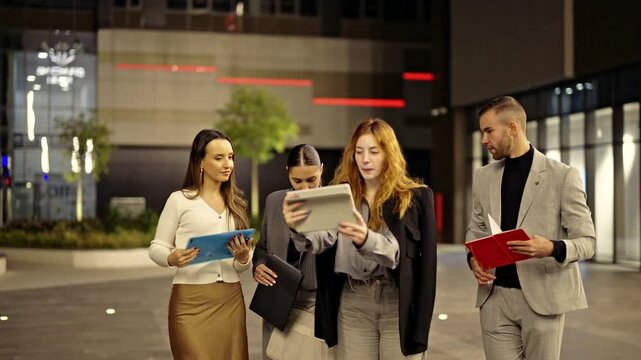 A team of business associates discuss project details on a tablet, fostering innovation and successful communication in the city.