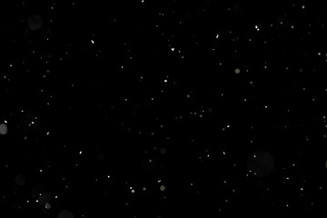 Bokeh effect of snowfall and lights. Abstract blurred background with snowflake in the night sky, White spots and dots in the dark. Snowy stormy weather, falling snow