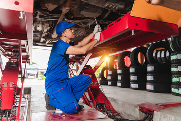 Skilled mechanic working under car on repair equipment, adjusting vehicle components in a modern automotive service station, focused on quality maintenance and safety