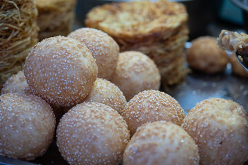 Close-up of traditional Chinese sesame balls (Jian Dui) at a local market in Yunnan, China. Fried glutinous rice pastries coated with sesame seeds, popular Asian dessert