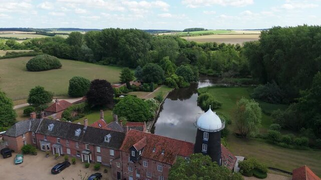 Ariel footage of Burnham Overy Staithe Mill in Norfolk England on the river Burn. Overy Water Mill, Windmill. Rural summer scene.