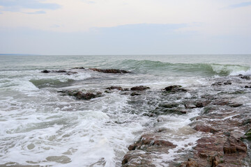 Old rocks on the seaside. Beautiful background of beach water flowing on the rocks.