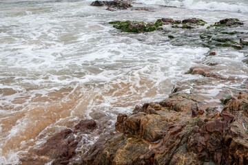 Old rocks on the seaside. Beautiful background of beach water flowing on the rocks.