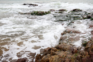 Old rocks on the seaside. Beautiful background of water flowing on the rocks, nature landscape.