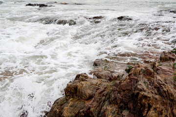 Old rocks on the seaside. Beautiful background of beach water flowing on the rocks.