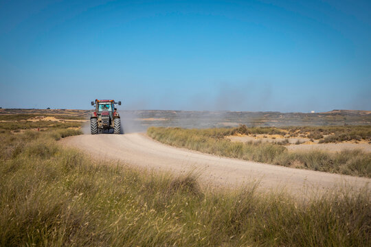 Dusty road rural landscape with vibrant blue sky and tractor driving, perfect for agriculture, farming, or construction projects adding authentic feel - Powered by Adobe