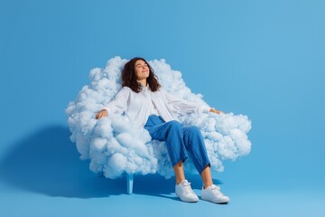 Happy young woman sitting on a cloud and enjoying. Lady wears white shirt and blue jeans sits on a armchair on blue background