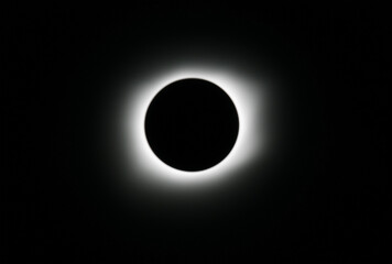 the total solar eclipse viewed from the ground shows a black sky with an almost completely dark circular area in the center of the frame