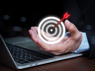 Business hand holding a glowing target symbol with arrow hitting the center, illustrating goal achievement and strategic planning. Concept emphasizes success, motivation, accuracy, business background