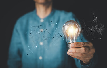 Man holding a glowing light bulb with icon network connection overlay, representing creative ideas, innovation, and digital transformation. Concept of business solution, technology, inspiration.