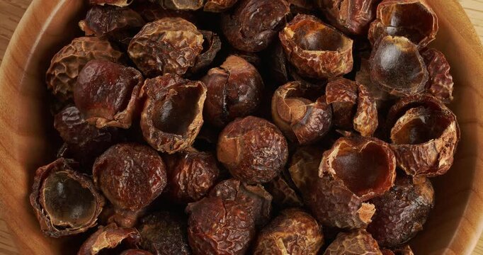 Soap nuts in wooden bowl, close-up footage on a rotating table.