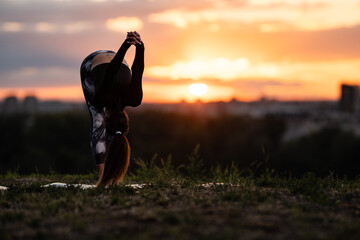 Young woman doing forward bend yoga pose at sunset
