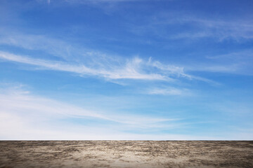 Empty textured ground with clear blue sky and soft clouds in background. Ideal for product mockup, copy space design, presentation, or conceptual freedom and nature background.