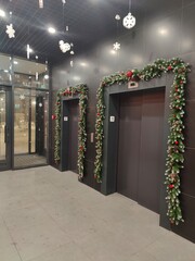 Elevator Lobby Decorated for Christmas Holidays. Modern building elevator area adorned with festive Christmas garlands, ornaments, and hanging snowflakes during holiday season celebrations