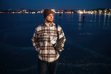 Obraz premium Standing and looking far away. A man is on the ice with his skates in winter