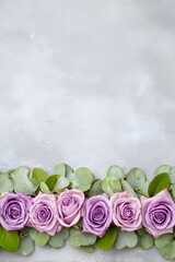 Beautiful lavender roses arranged on a neutral background with fresh green leaves in a simple yet elegant design