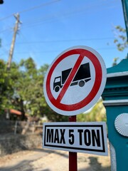 Close view of a “Max 5 Ton” traffic sign with power lines and bright blue sky in the background.
