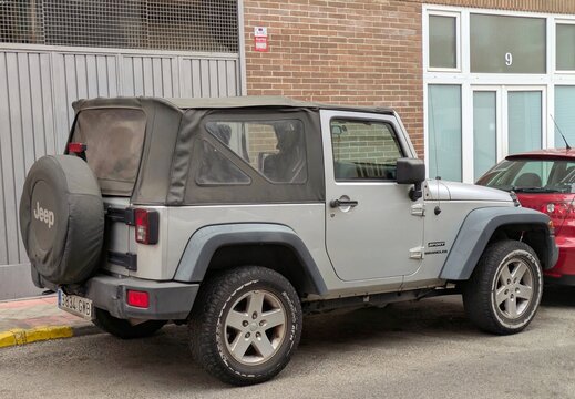Vista trasera de un autom&oacute;vil Jeep Wrangler, con capota de pl&aacute;stico y rueda de repuesto exterior, aparcado en una calle de Madrid, Espa&ntilde;a, 13 de octubre de 2025