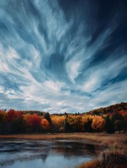 Naklejka premium Vibrant autumn forest landscape under a dynamic sky with diverse cloud formations highlighting seasonal change