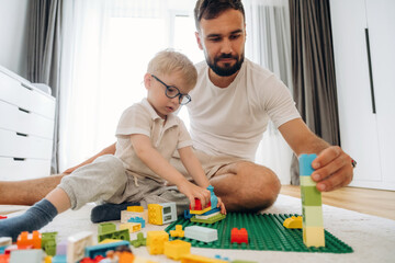 Fototapeta premium Father is playing in the room with his little son with construction sets
