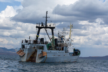 Commercial Fishing Trawler Ship Sailing on Ocean Under Cloudy Sky