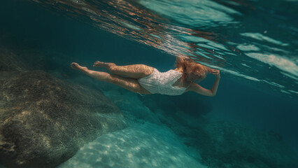 Woman with blonde hair in a lace white dress underwater