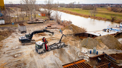 Aerial view on excavator and tow truck as they move part of vessel