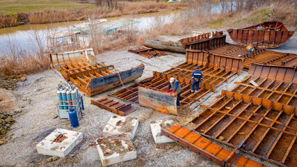 Aerial view on workers as they manually cutting old ship with blowtorch, mixing oxygen and...