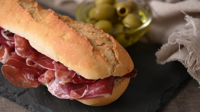 Spanish serrano ham sandwich on wooden table. Spanish bocadillo de jamon serrano