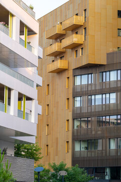 Golden facade apartment buildings in Montpellier, France, illuminated by evening light and surrounded by modern white structures, representing elegant urban harmony and architectural sophistication
