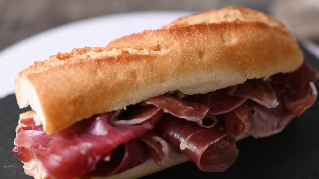 Spanish serrano ham sandwich on wooden table. Spanish bocadillo de jamon serrano