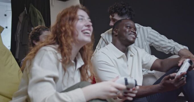Diverse colleagues enjoy a break at work, playing video games and having fun together. Teamwork, relaxation, and entertainment in the startup environment.