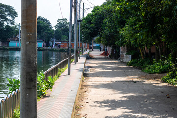 Obraz premium Discover peaceful lakeside strolls along serene paths shaded by lush trees in charming rural villages, inviting calm and relaxation on sunny days