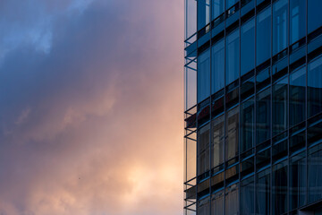 Detail of contemporary architecture with blue glass facade and reflections under evening light offering copy space for modern branding layout