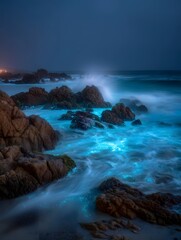Bioluminescent ocean waves crash dramatically on a rocky shore under a dark misty night sky