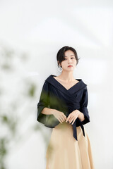 Elegant woman in a navy blouse and beige skirt standing gracefully indoors.