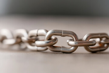 Obraz premium Metal Chain Link - Silver-toned metal chain links are displayed in an up-close shot, laid flat. The metallic surface gleams in soft lighting.