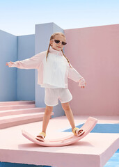 Child balancing on pink rocking toy in casual summer outfit outdoors.