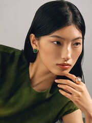 Woman in green top with elegant jewelry showcasing modern beauty.