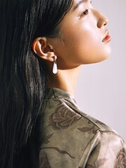 A profile portrait of a woman wearing floral patterned attire and elegant earrings.