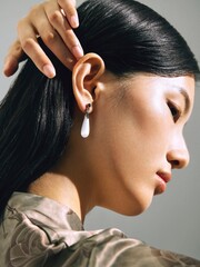 Profile shot of an Asian woman with elegant earrings and long hair. © Guisheng
