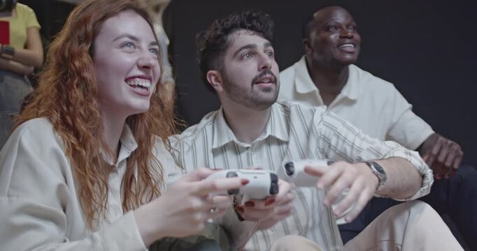 Diverse colleagues enjoy a break at work playing video games. They laugh, strategize, and bond over friendly competition, showcasing camaraderie in a modern office environment.