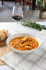 Chickpea stew with meat and chorizo served with red wine