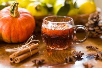 Autumn composition with pumpkin, quince and cup of tea with star anise on wooden table