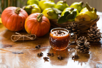 Autumn composition with pumpkin, quince and cup of tea with star anise on wooden table