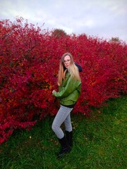 Young woman in a green jacket on a background of autumn leaves.