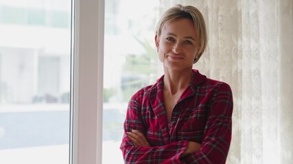 Young woman in red plaid pajamas opens the window, letting in fresh air. Her posture reflects relief and renewed energy. Concept of recovery, wellness, and fresh start. Back view, natural light, mid - Powered by Adobe