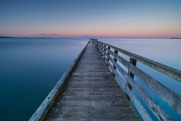 Obraz premium ニュージーランド オークランドの郊外にあるコーンウォリス・ビーチの夕暮れ時の桟橋の上からの風景