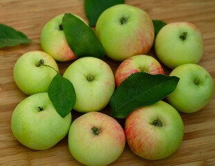 Some fresh organic apples with leaves on a wooden background